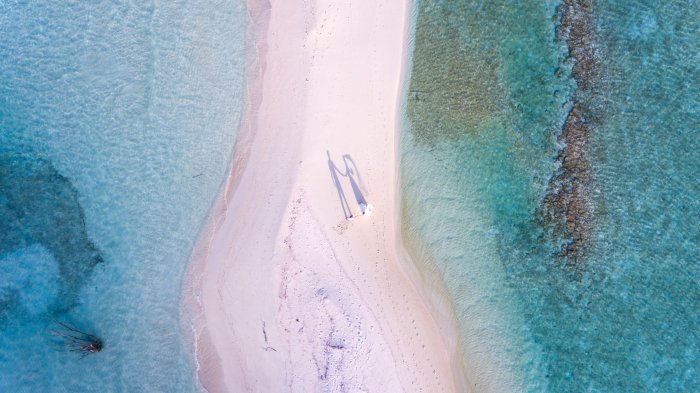 pink sand beach with crystal clear blue sea on each side destination wedding
