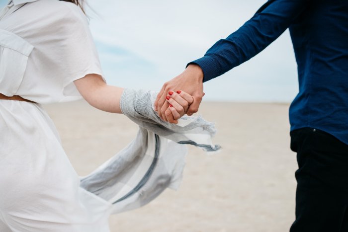 woman and man holding hands on the beach at destination wedding