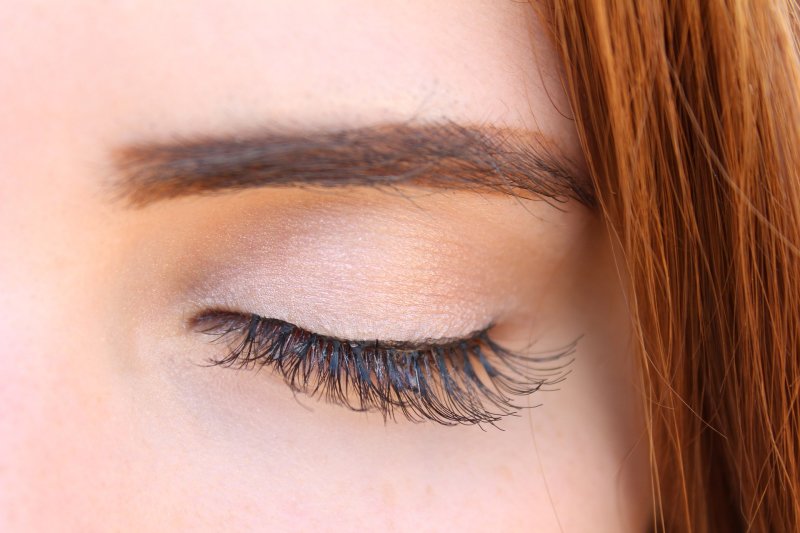 Girl with red hair and one eye closed with lash extensions 