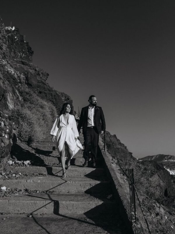 stylish Santorini elopement couple walking hand in hand in santorini