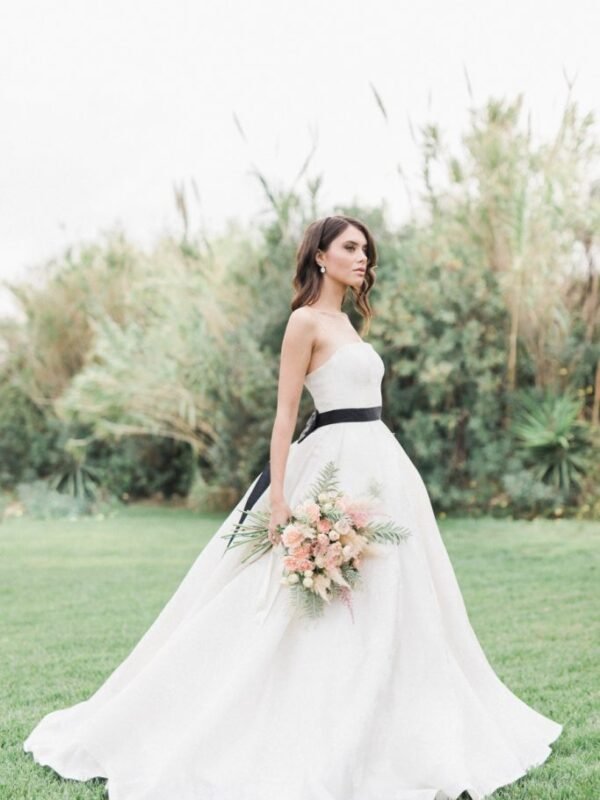 Bride with white dress and black belt holding a bridal bouquet