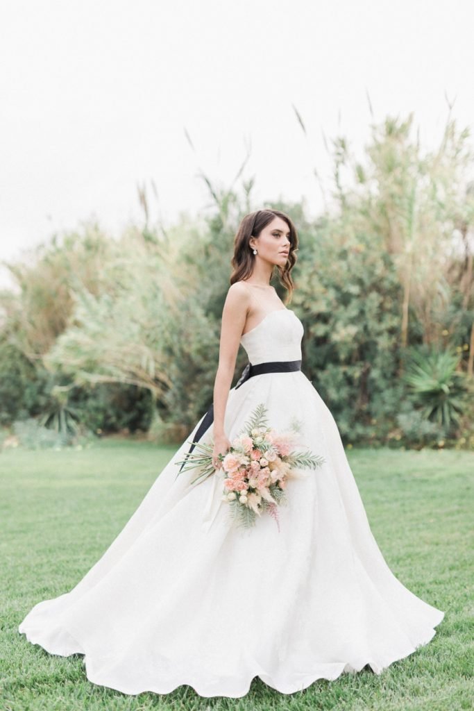 Bride with white dress and black belt holding a bridal bouquet 