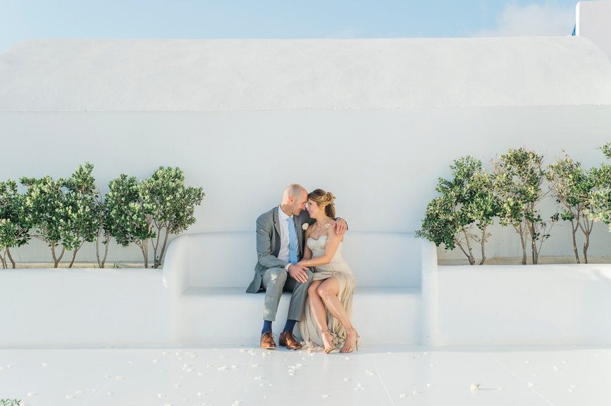 Hellenic Chic Elopement couple sitting on the white bench on the rooftop terrace on Santorini