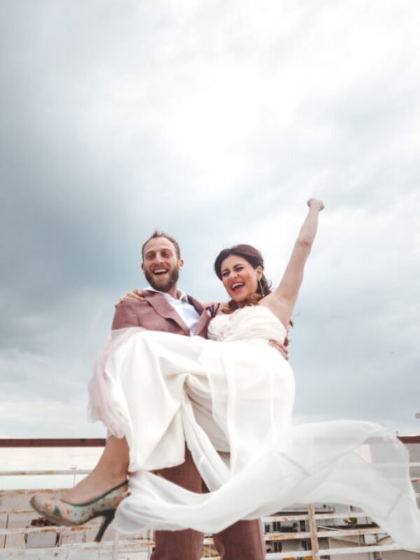 Happy Groom holding a happy Bride on the rooftop when they postpone their wedding