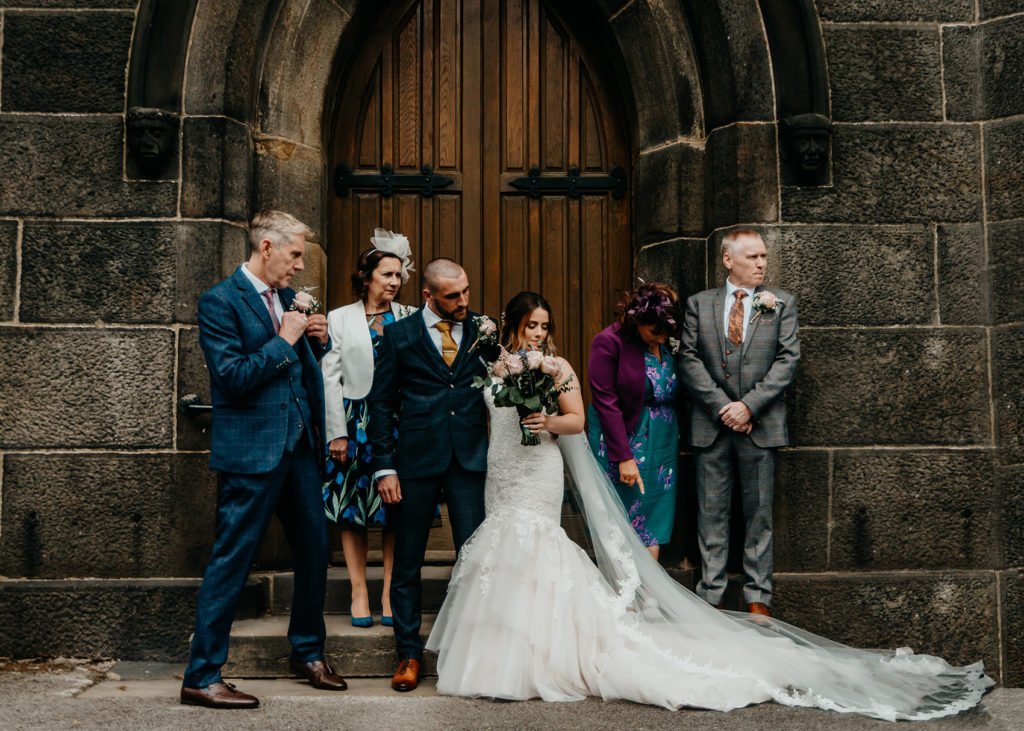 Family portrait in front of the church doors with smart dressed parents