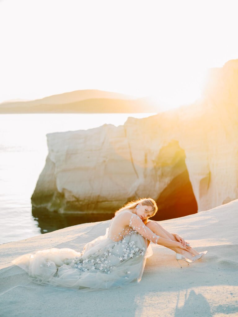 Bride sitting on the cliffs at Milos beach