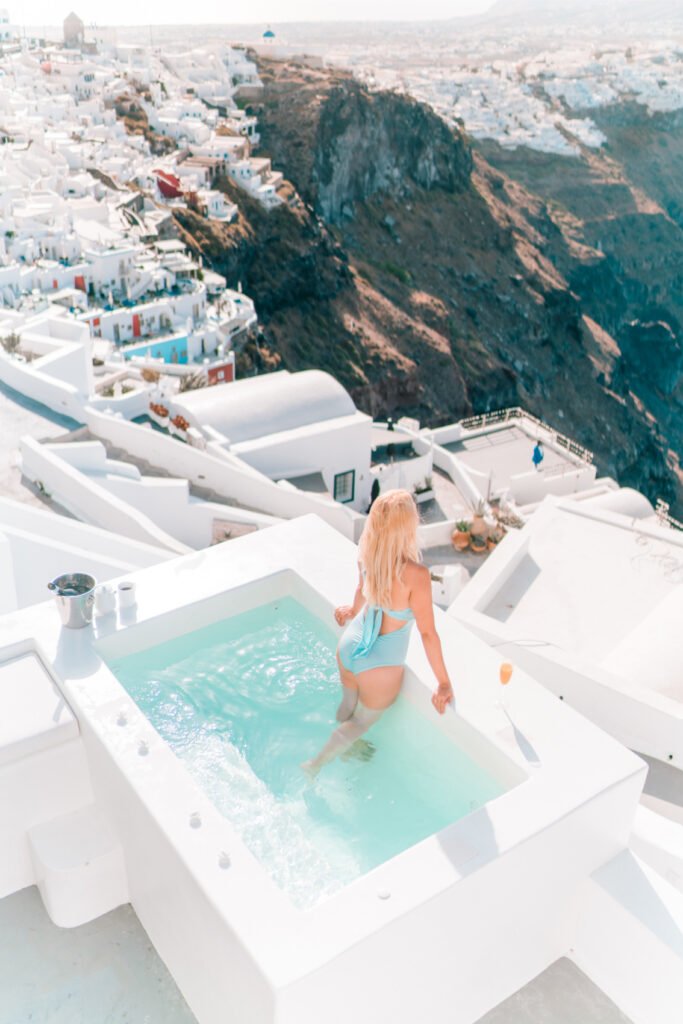 Girl Instagram Influencer in the pool in Santorini overlooking the town
