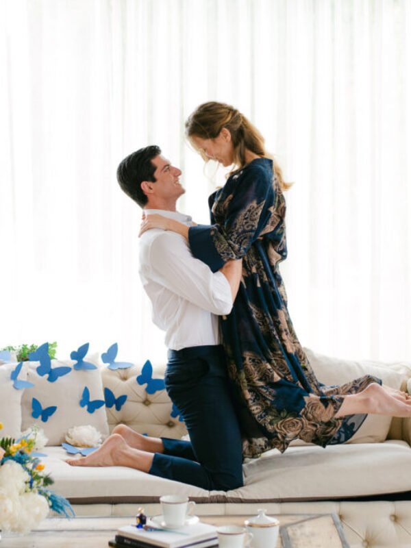 True Blue Luxury Wedding Inspiration Groom lifting the bride with joy on the couch decorated with butterflies