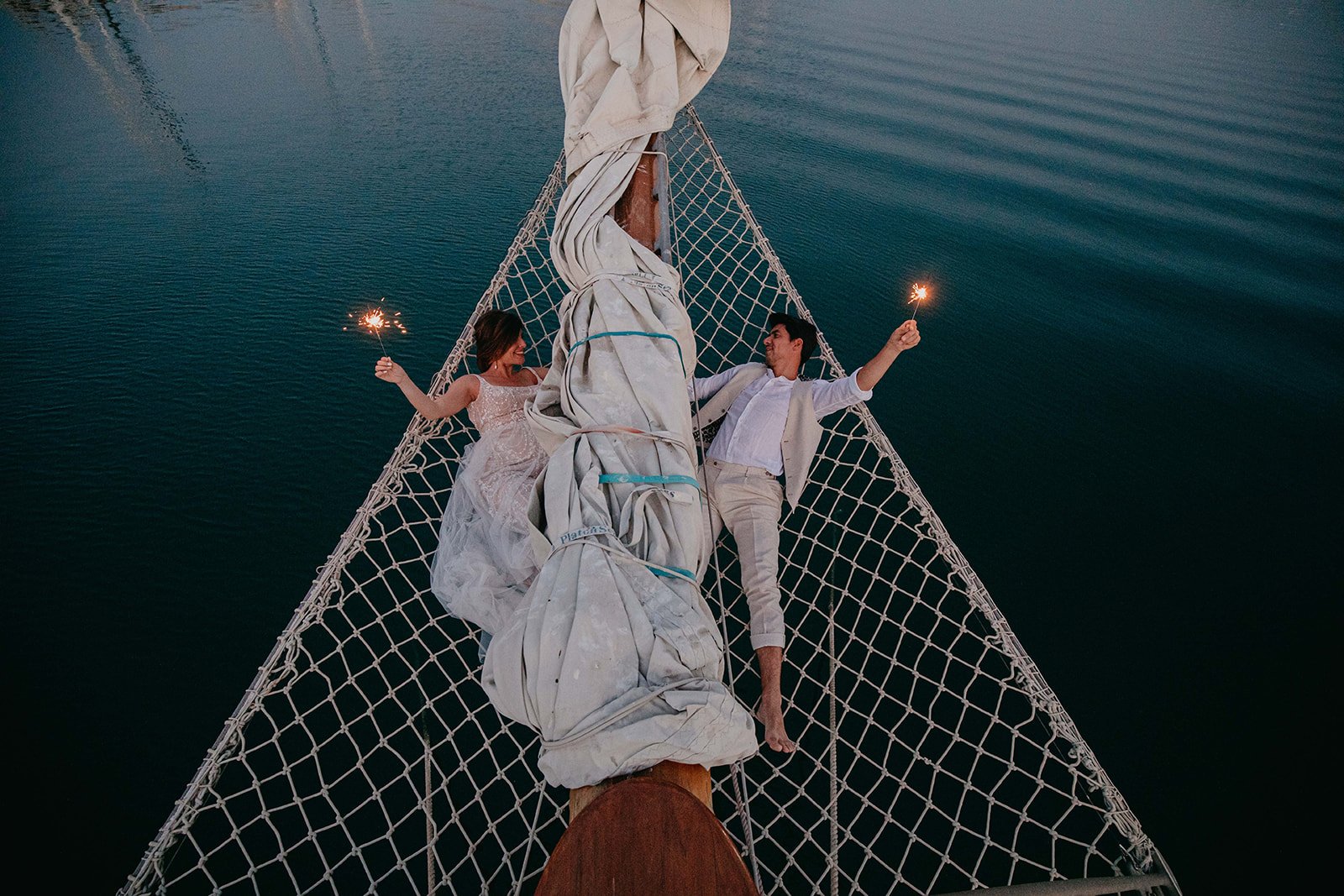 Elopement Shoot on a Historic Yacht Bride and groom lying on the net above the water