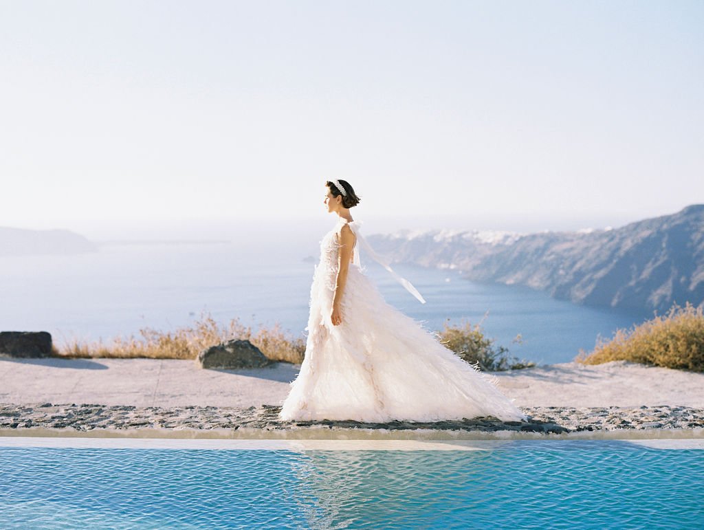 Bride walking by the pool with the view of the sea and cliffs 