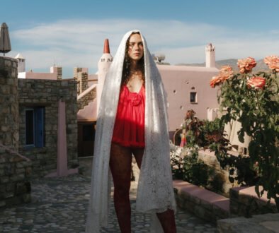 No-Décor No-Venue Wedding in Naxos Bride standing in front of a unique pink villa in Red Dress and white lace veil