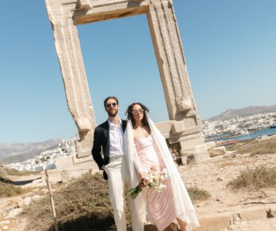 Things to consider for a wedding on a Greek island. Groom and bride standing in front of Naxos Portara monument