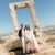 Things to consider for a wedding on a Greek island. Groom and bride standing in front of Naxos Portara monument