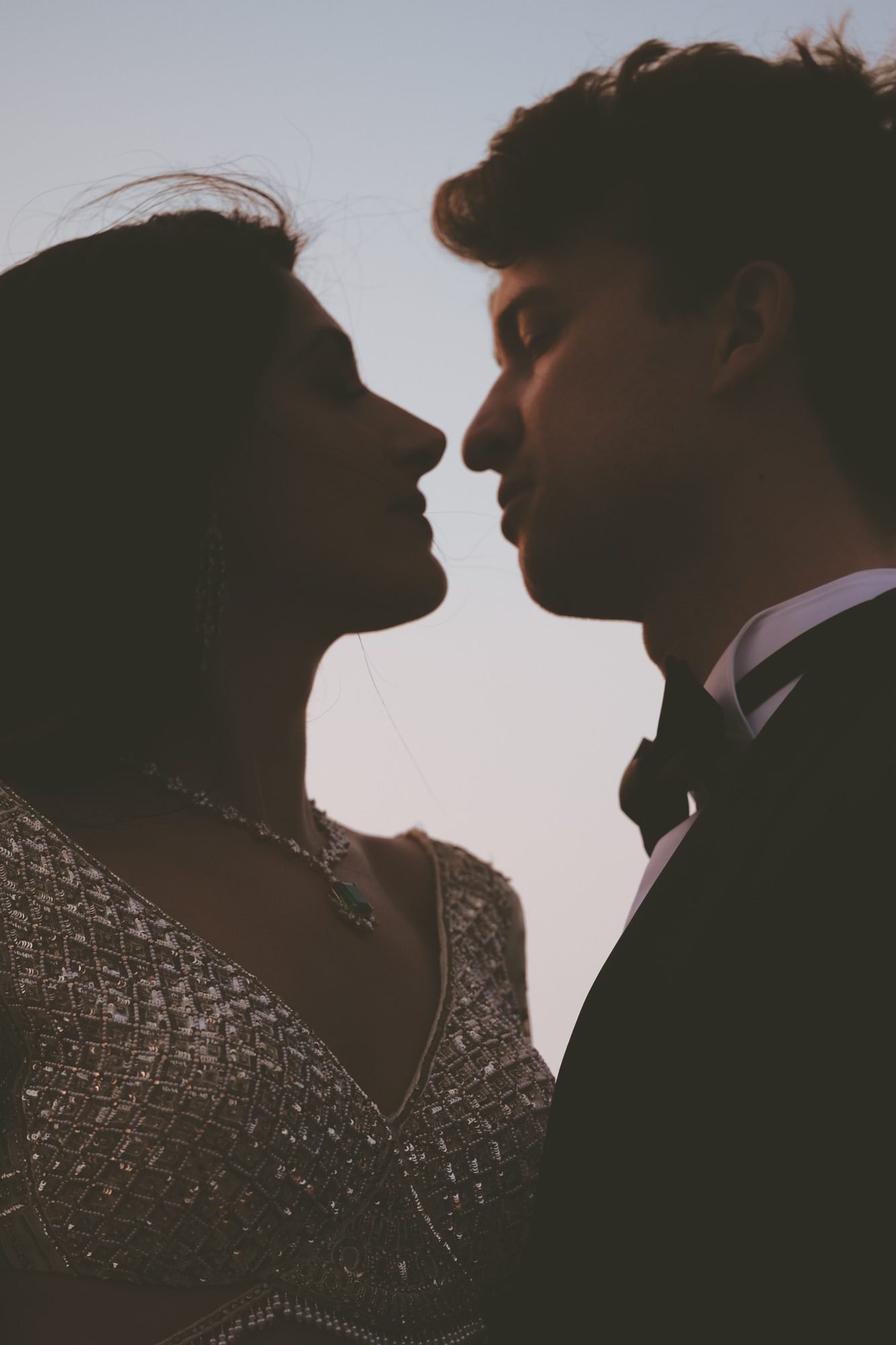 Dark portrait of a bride wearing a white gold dress and groom in a black tuxedo