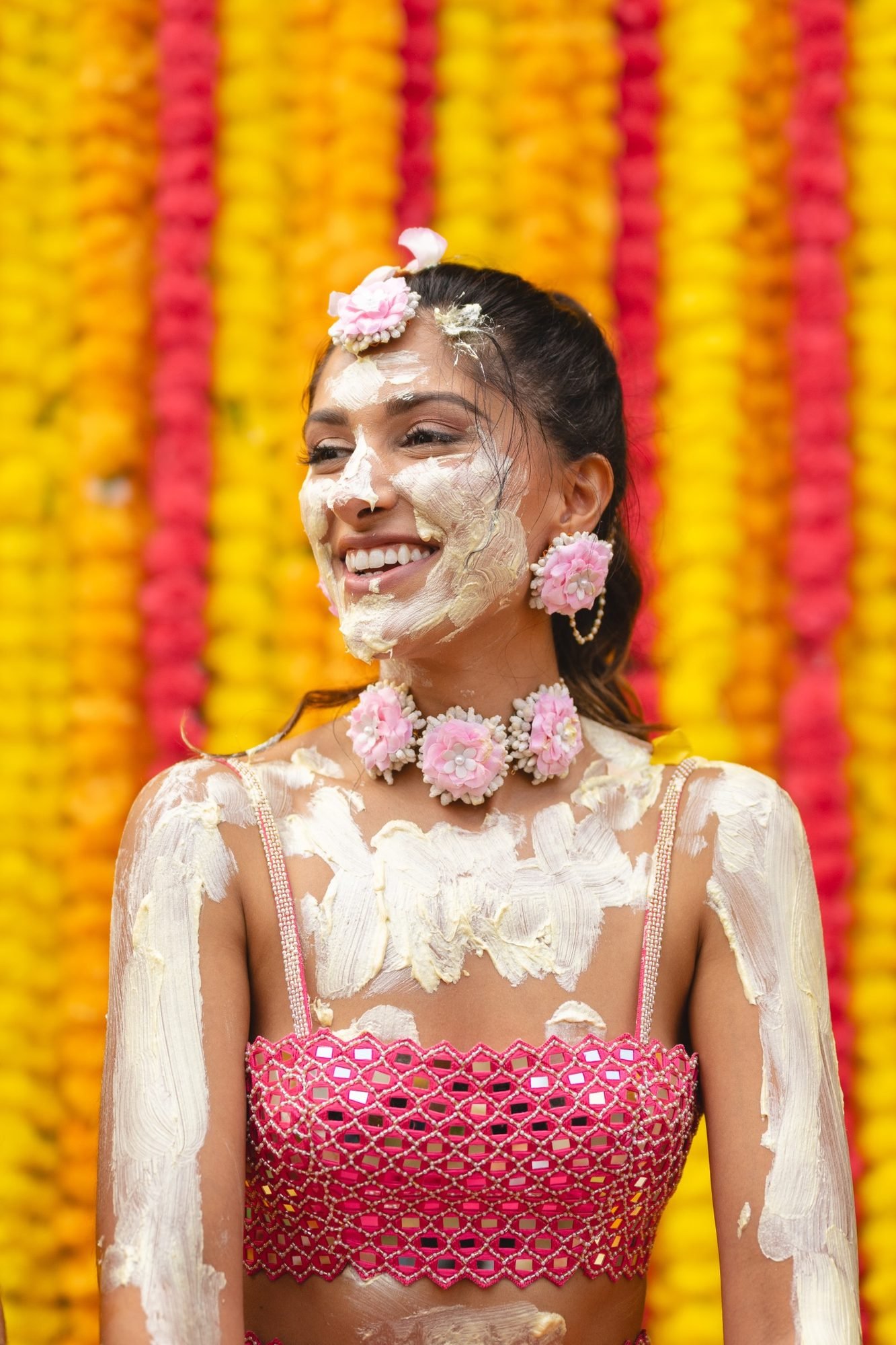 Painted bride in pink smiling at her beachfront Haldi and Mehndi celebration in the Athenian Riviera