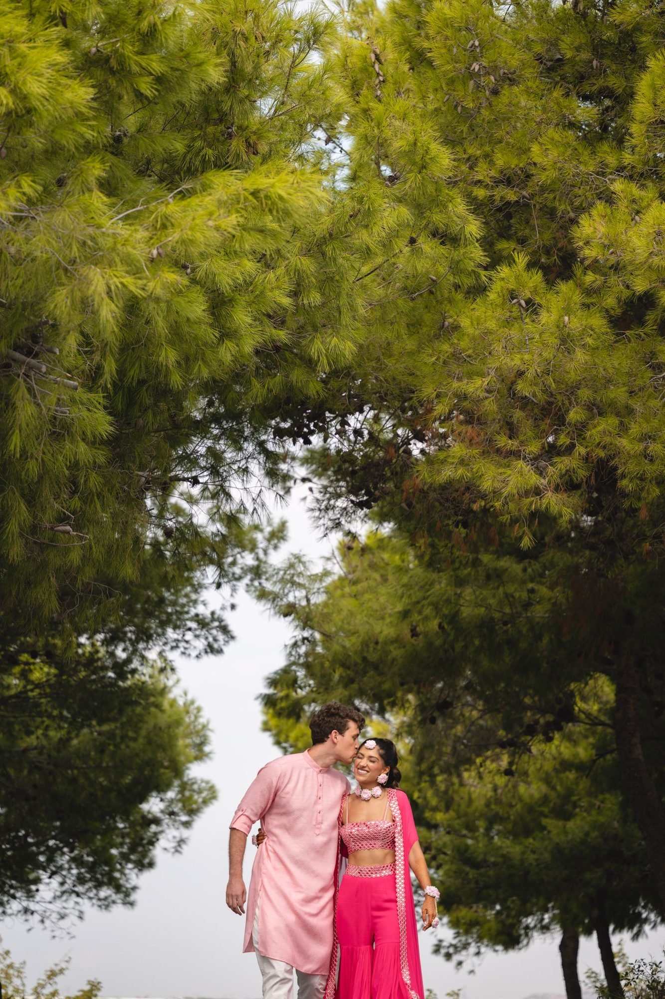 Bride and Groom both dressed in pink waling in the forest at the Grand Resort Lagonissi