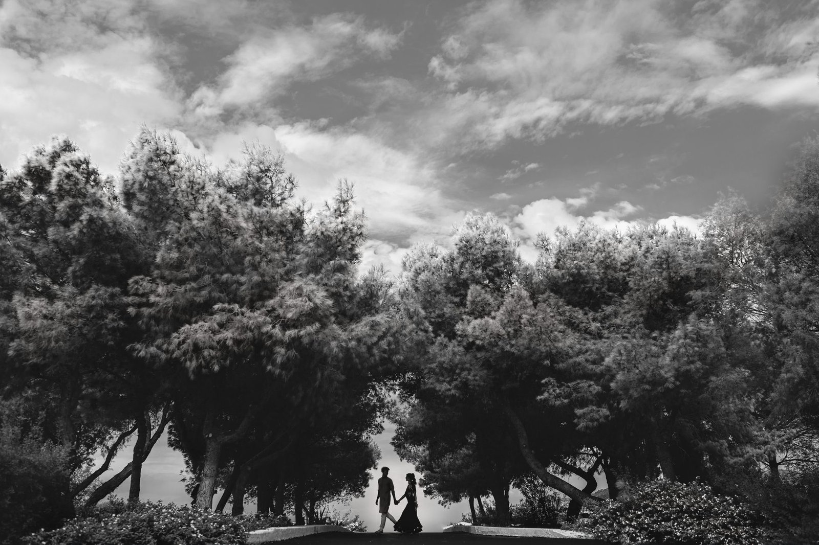 Black and White image of a bride and Groom holding hands and walking in the Mediterranean forest in Athens Riviera Greece