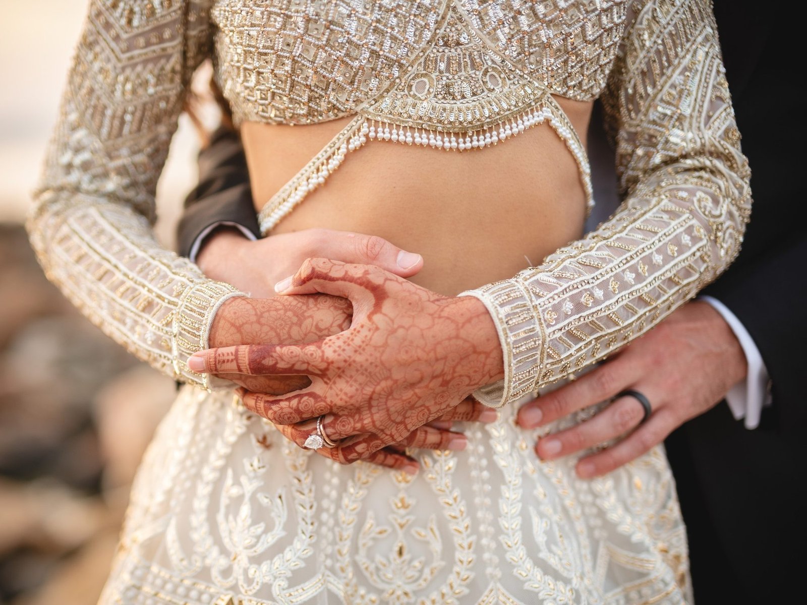 Closeup image of Bride wearing a white gold foil Falguni Shane Peacock Lehenga and groom hugging her