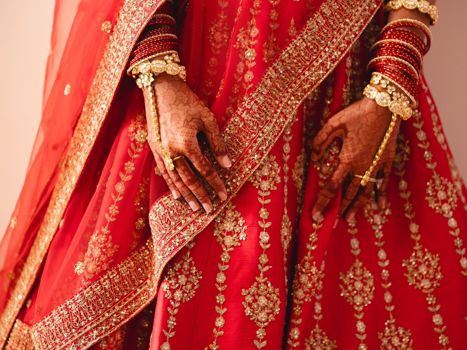 Closeup of a bride in red and gold bridal Lehenga showing her bridal Mehndi and gold Indian Jewellery with diamonds at her destination Indian wedding in Greece