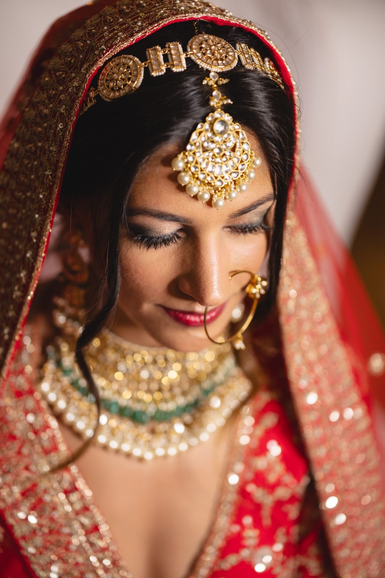 Closeup portrait of an Indian Bride in in red bridal Lehengaa and Indian Gold Jewellery for Indian wedding in Greece at Grand Resort Lagonissi Hotel Venue 