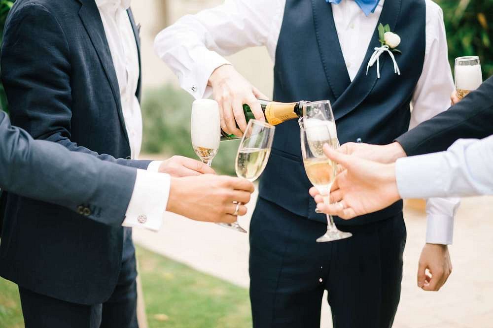 Closeup of groom pouring champagne to his guests at their intimate wedding in Greece.