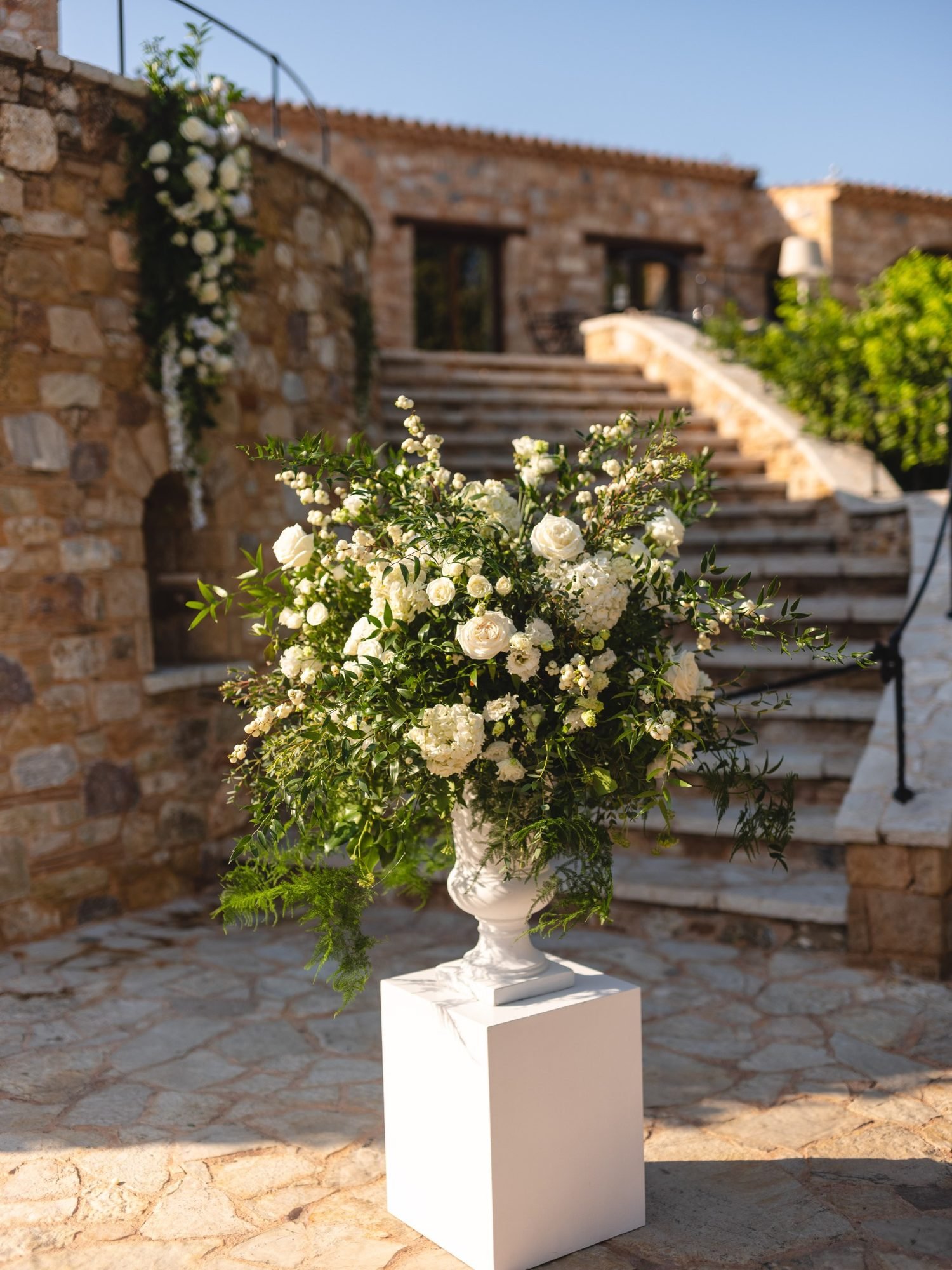 Classic rustic white wedding decoration with white roses and green foliage for a Christian ceremony at the Pryrgos Petreza vineyard in Athens Greece