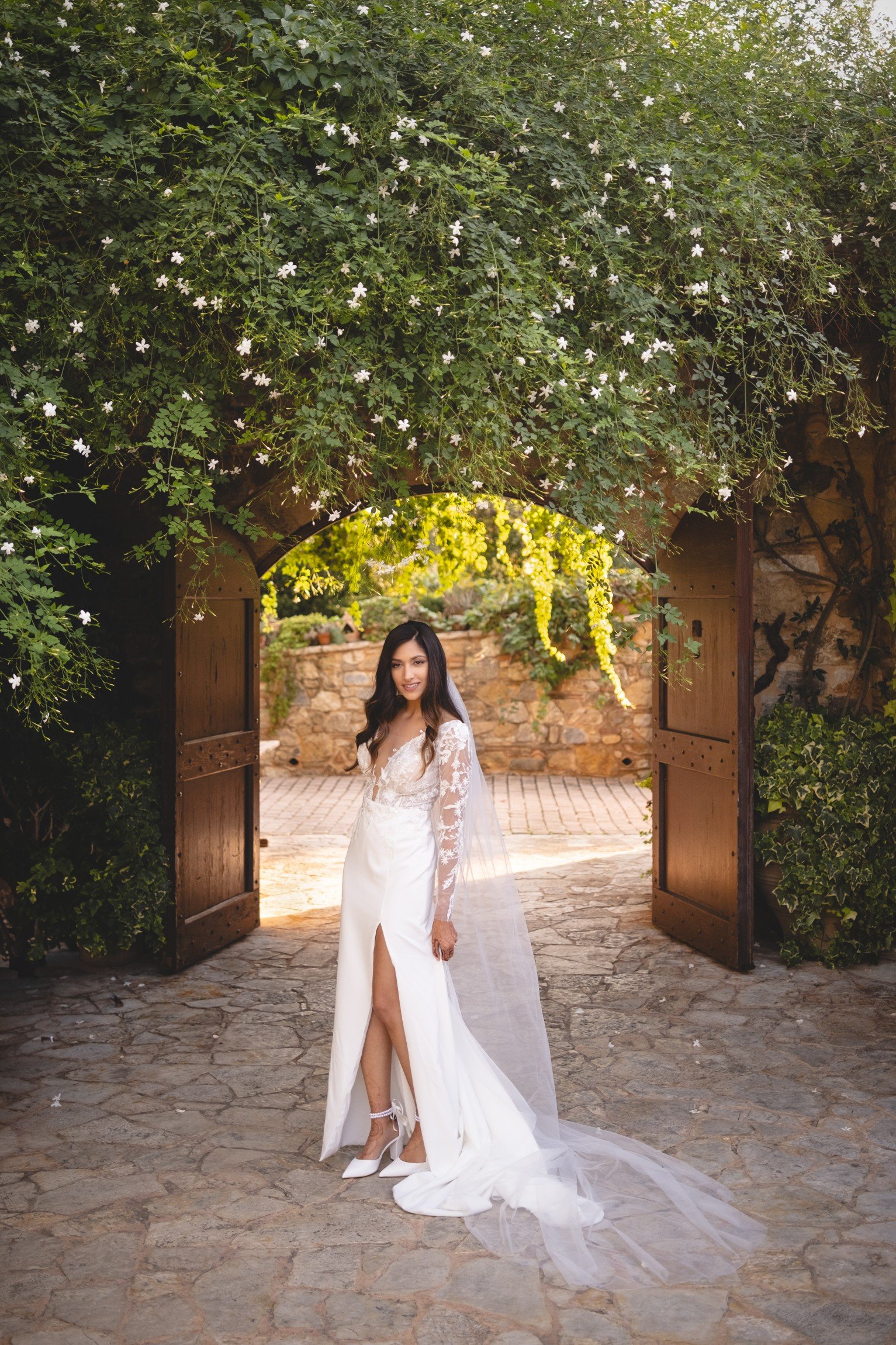 Bride in a white wedding dress showing her bridal Mehndi next to the door at Pyrgos Petreza vineyard venue in Greece