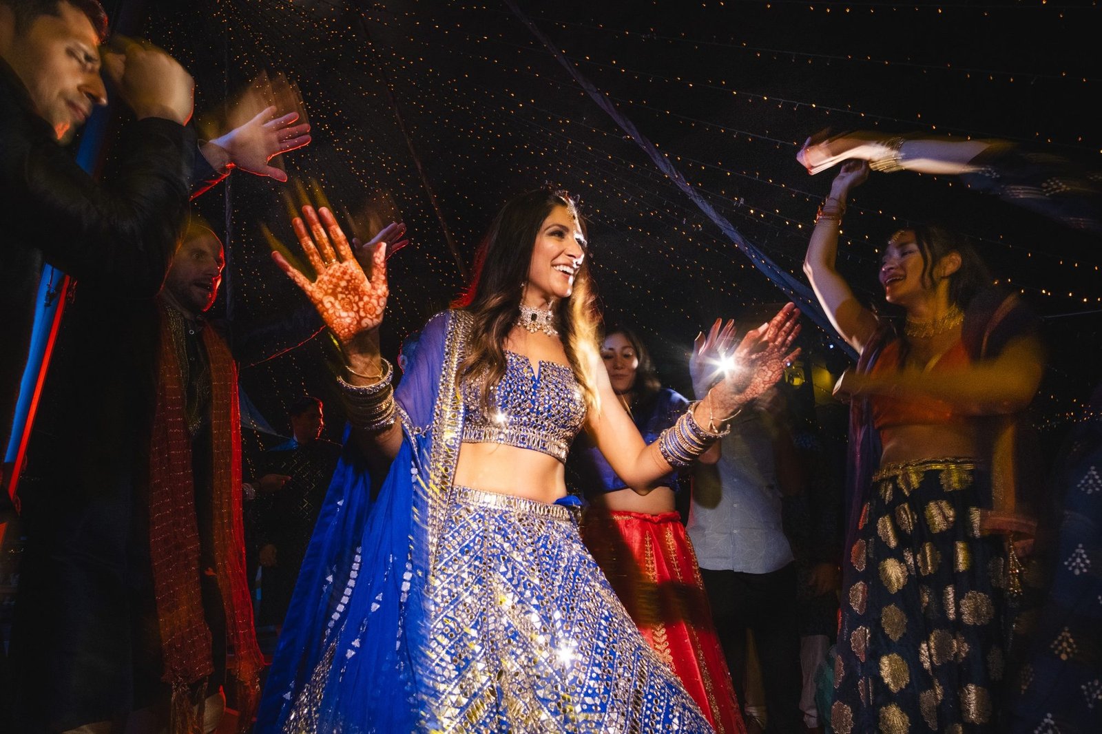 Bride dancing at an outdoor Sangeet venue, wearing a royal blue mirror embroidery Seema Gujral Lehenga