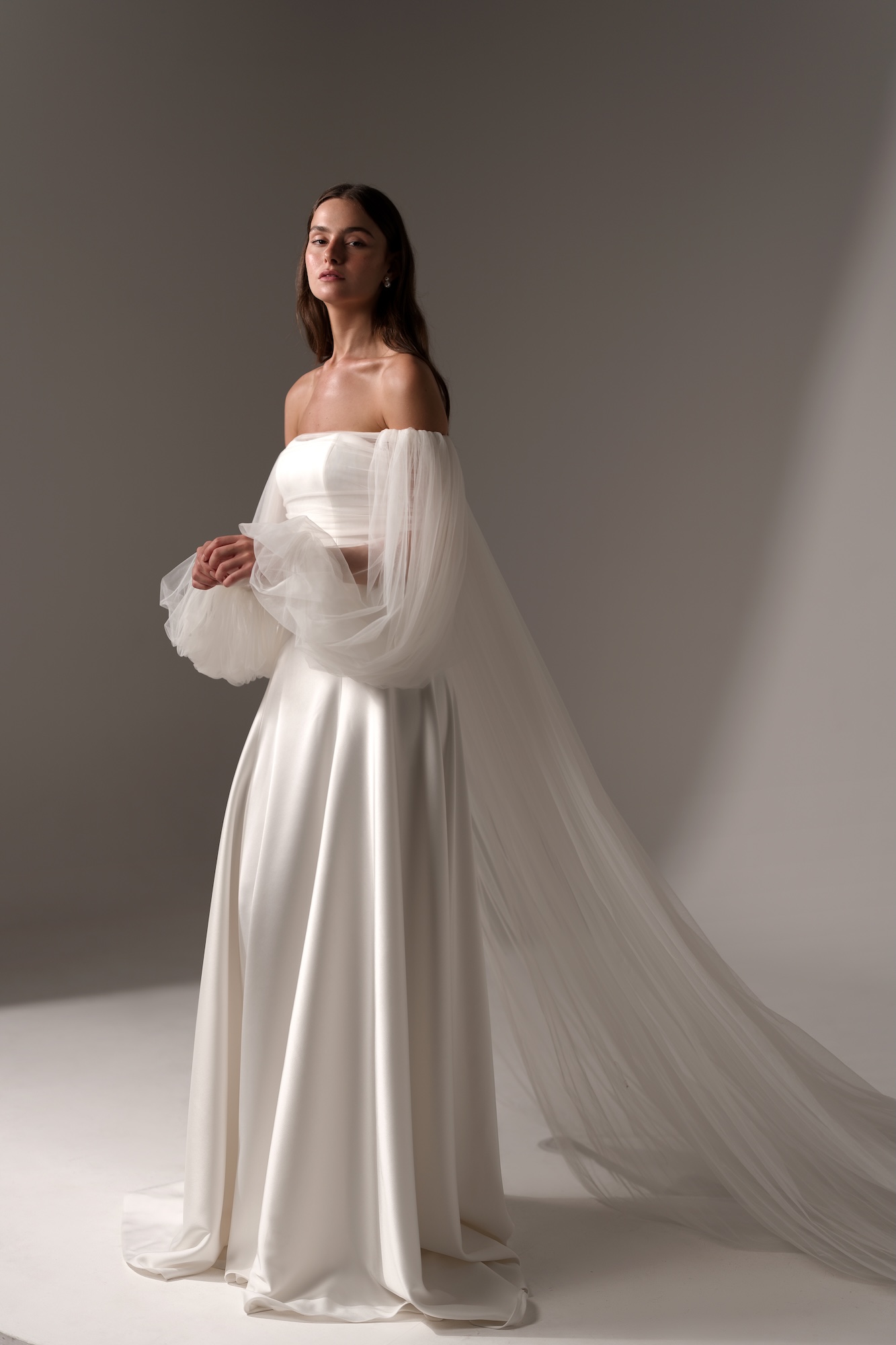 Alma by Lihi Hod, a timeless silk satin A-line gown with a clean strapless neckline and a structured, minimalist bodice. The sleek silhouette gently flares into a fluid skirt, finished with fabric-covered buttons along the back
and a graceful, sweeping train.
