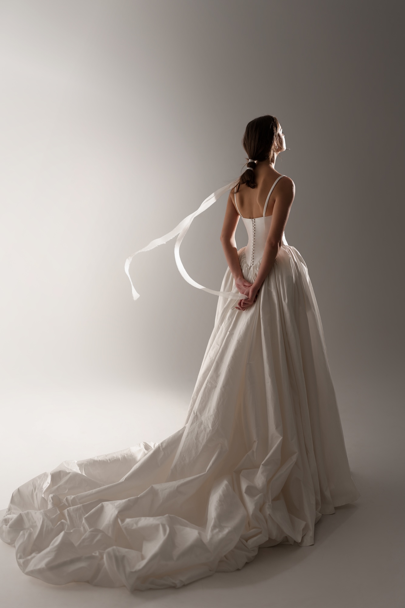 Liri a romantic silk Shantung ball gown the sculpted basque waist flows into a voluminous, softly gathered skirt that extends into a
dramatic cathedral-length train