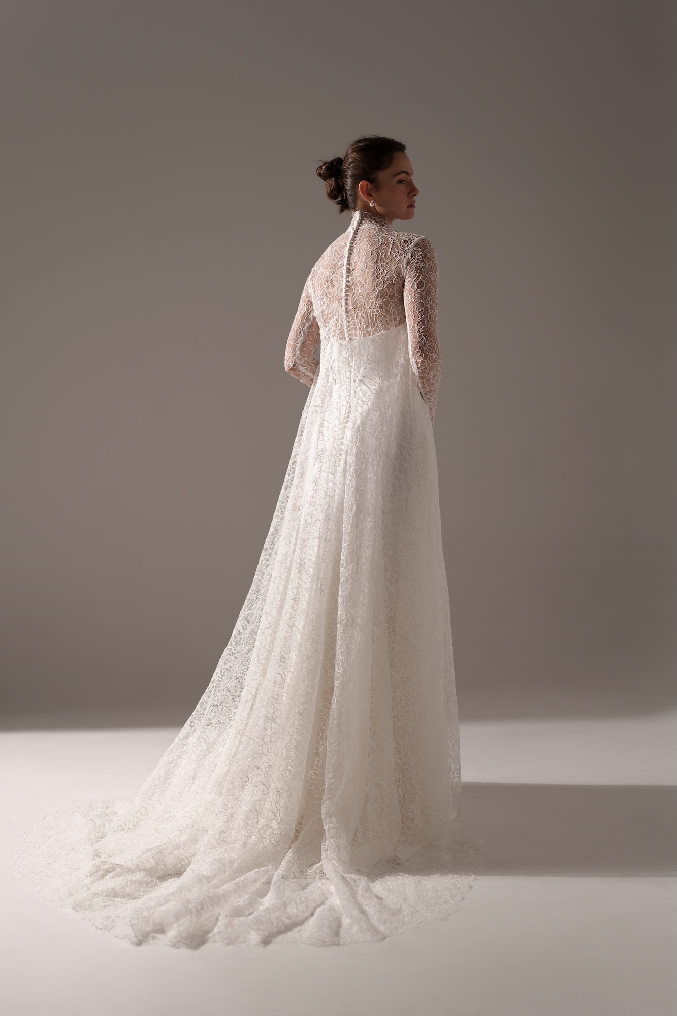 Back of Muse by Lihi Hod, minimalist silk satin A-line wedding dress with with delicate sheer lace long sleeve and cape topper with fabric-covered buttons along the back