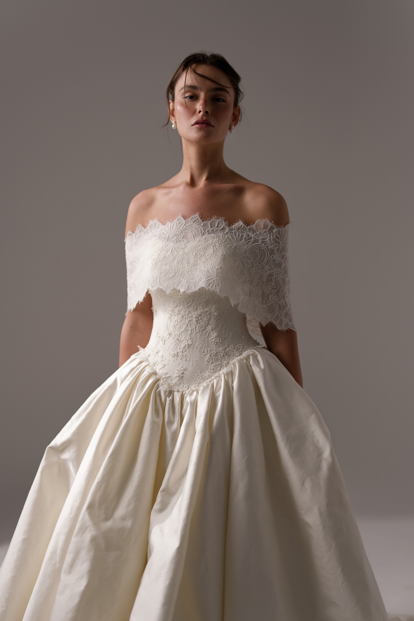 The Odyssee by Lihi Hod a dreamy silk duchess satin wedding dress
with a lace shoulder topper, hand-beaded lace structured corseted and a curved basque waist.