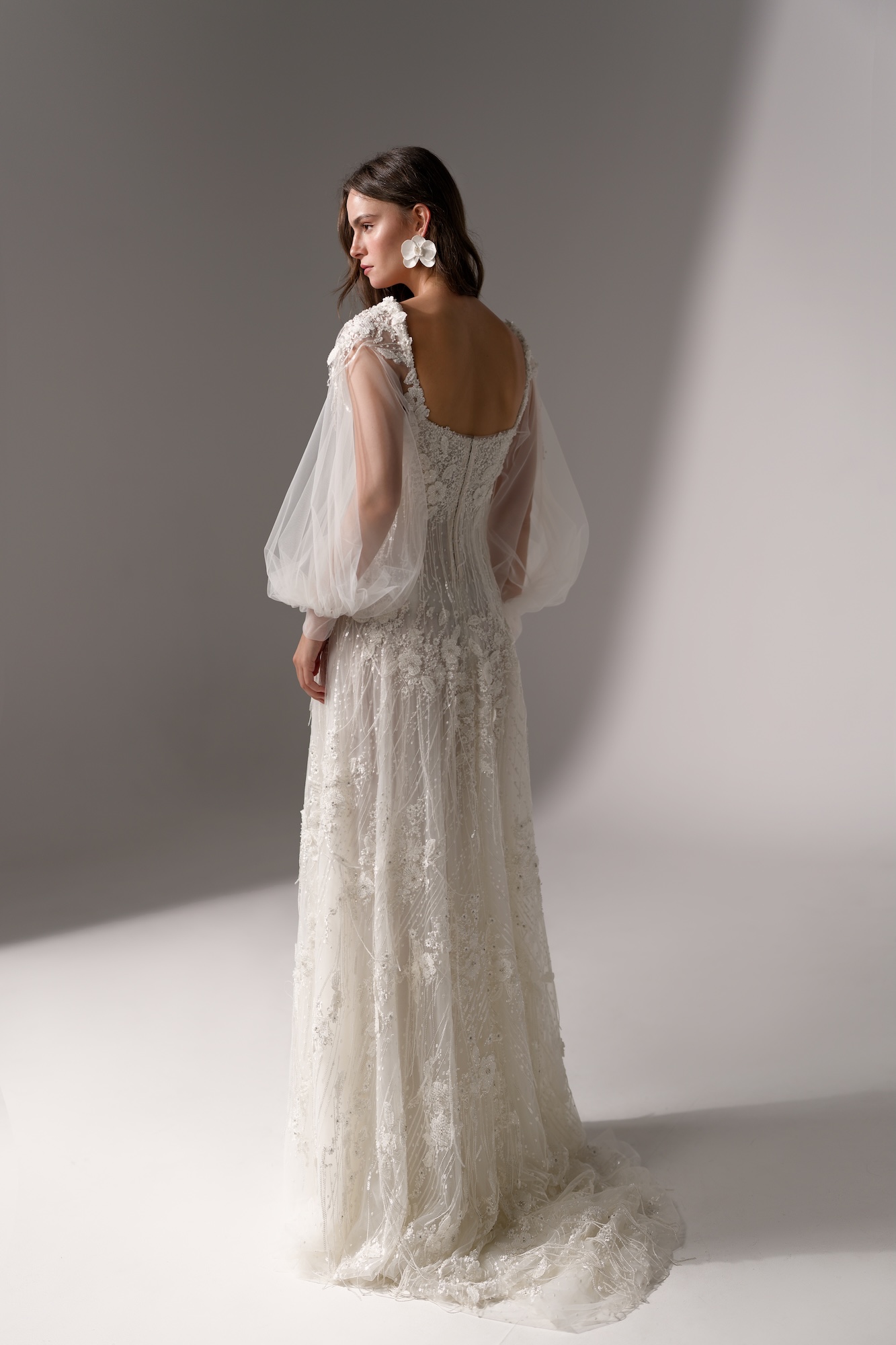 Back of Ever by Lihi Hod, figure-skimming wedding dress with hand-beaded floral appliqués and sheer tulle sleeves, completed by a softly scooped back and a graceful train.