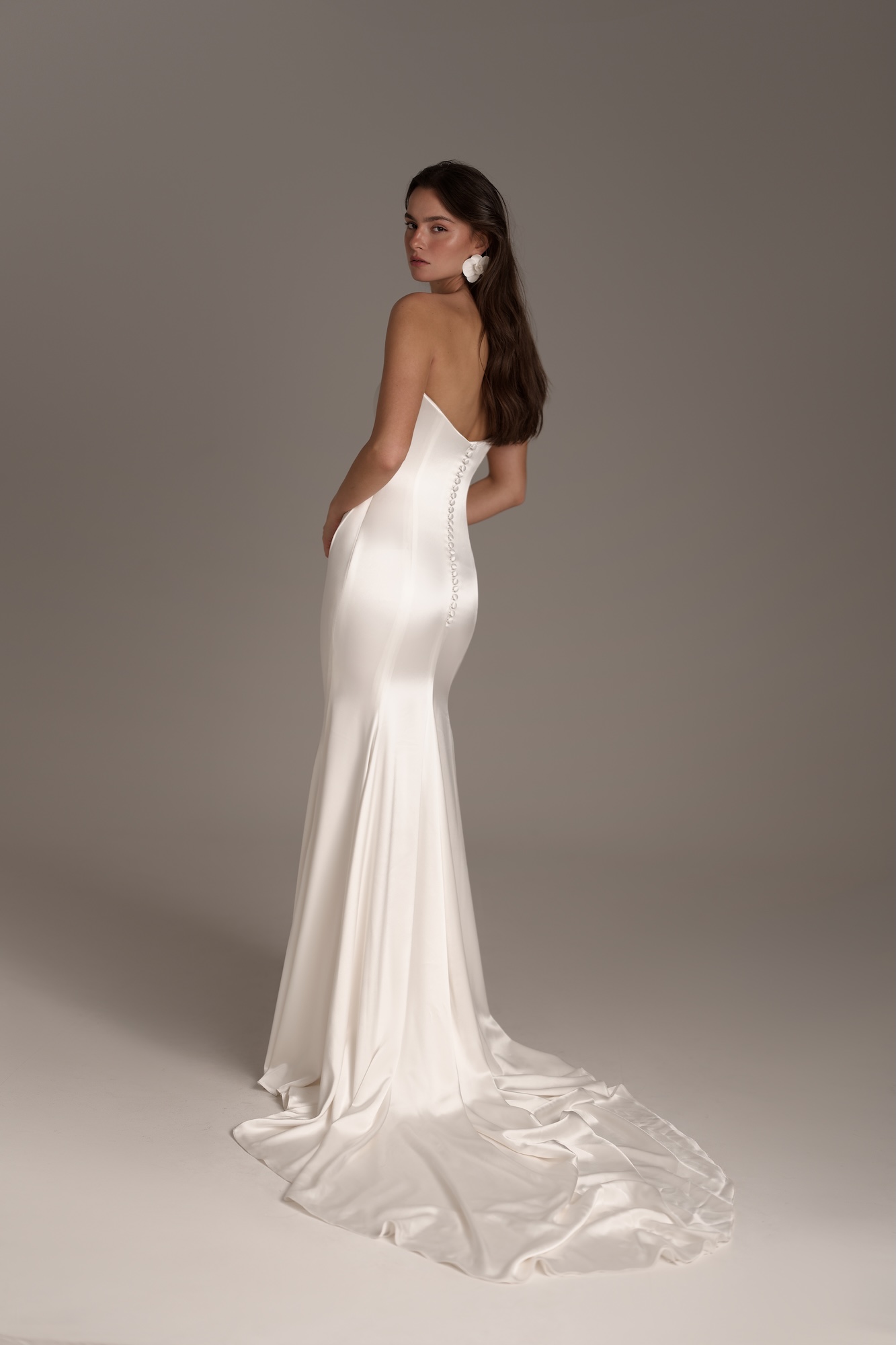 Back of Ophelia an elegant silk satin clean strapless fit-and-flare gown, fitted bodice accentuating the waist and hips before flowing into a sleek, fluid skirt and a graceful train with a low-cut back, with fabric-covered buttons along the back