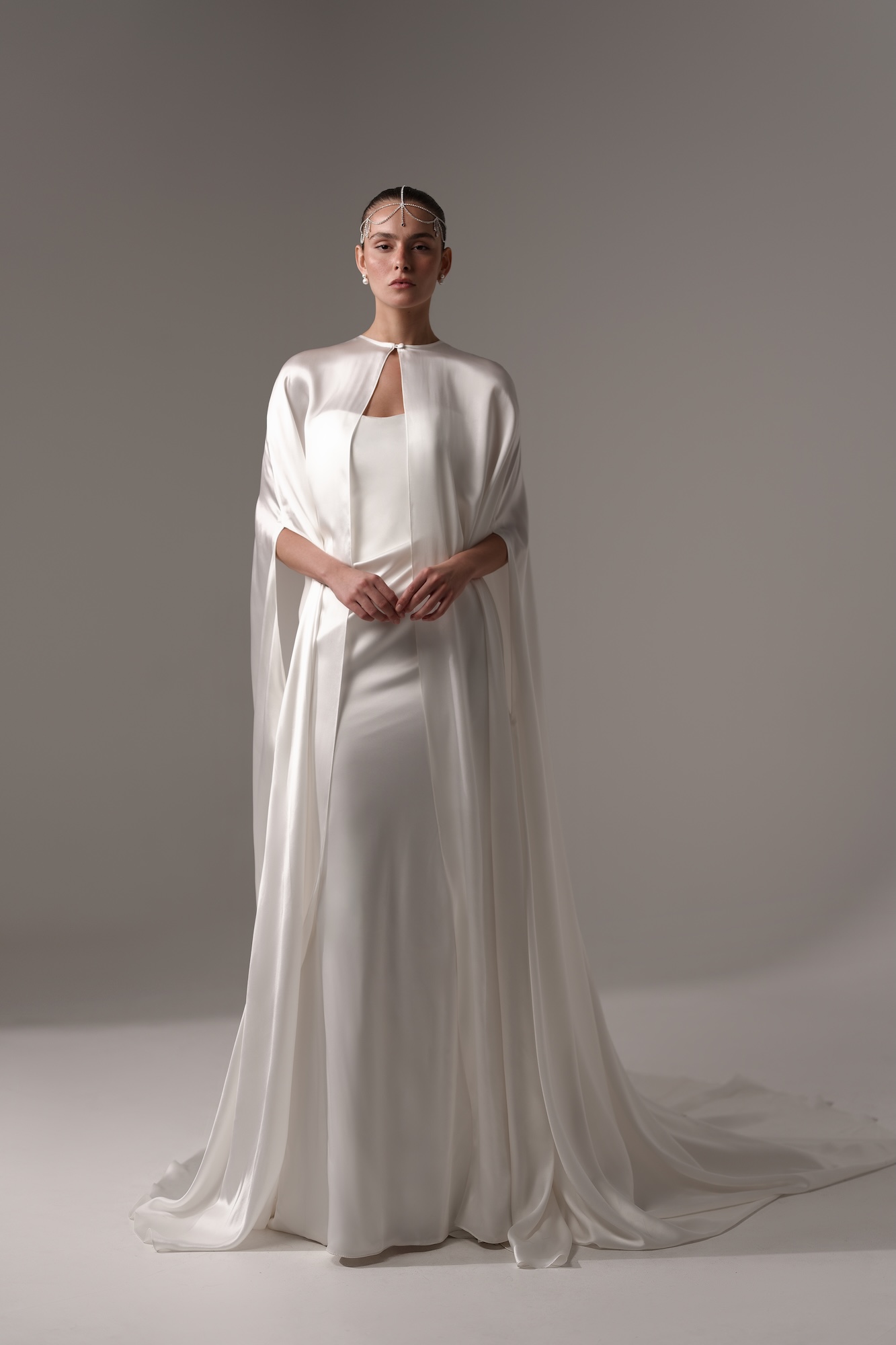 Ophelia dreamy wedding dress with long satin sleek cape top and head jewelry bring the Greek Goddess vibes for Odyssée 2027 bridal collection by Lihi Hod inspired by romantic fantasy cinema