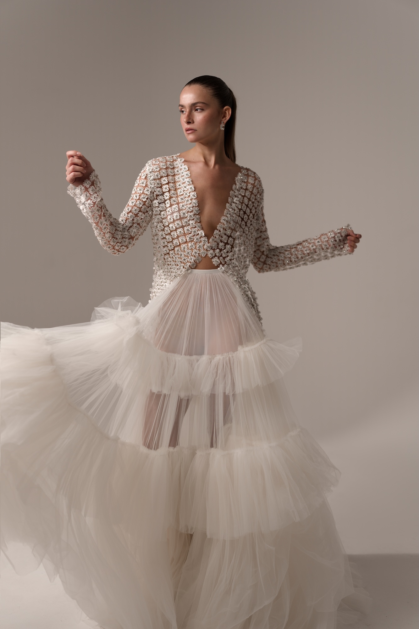 Rise and Shine is a statement bridal ensemble featuring an intricately embellished, long-sleeve open jacket paired with a voluminous, multi-tiered tulle skirt. Cascading layers of airy tulle add dramatic volume, movement, and a textured finish.