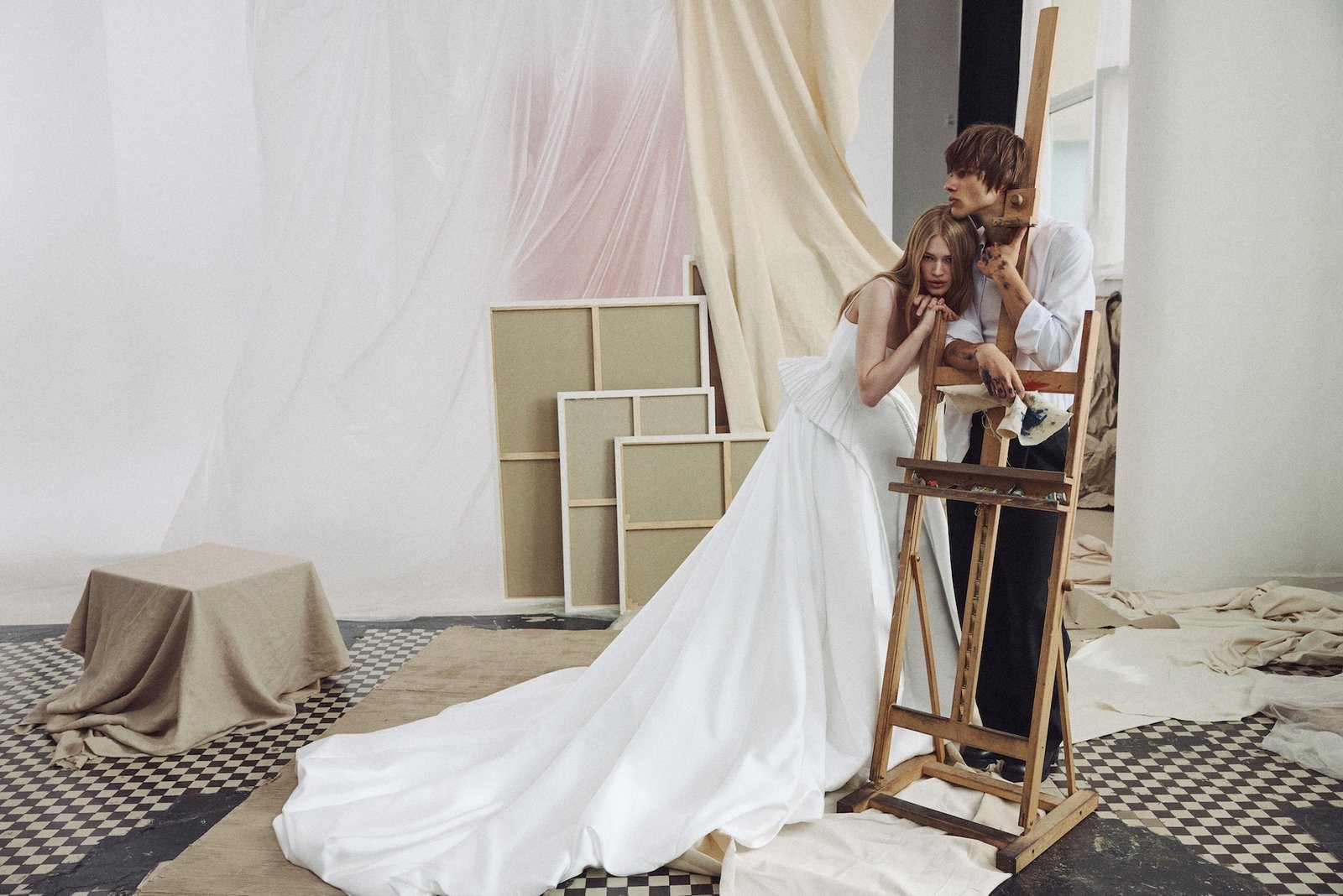 sculptural long wedding dress with architectural details posing in an artist studio