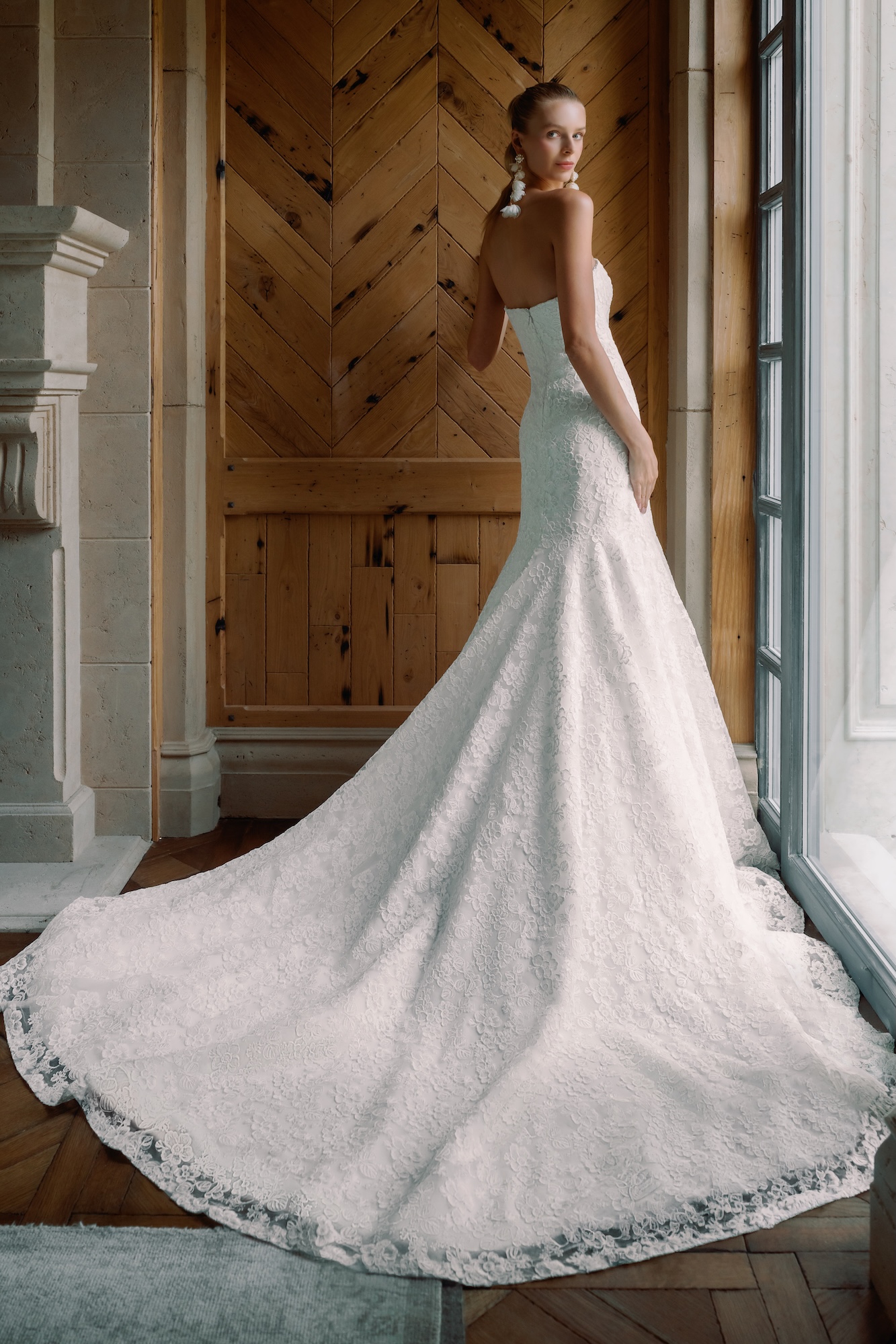 Backside of Love Story wedding dress with embroidered lace a dramatic fit-and-flare long skirt and long earrings 