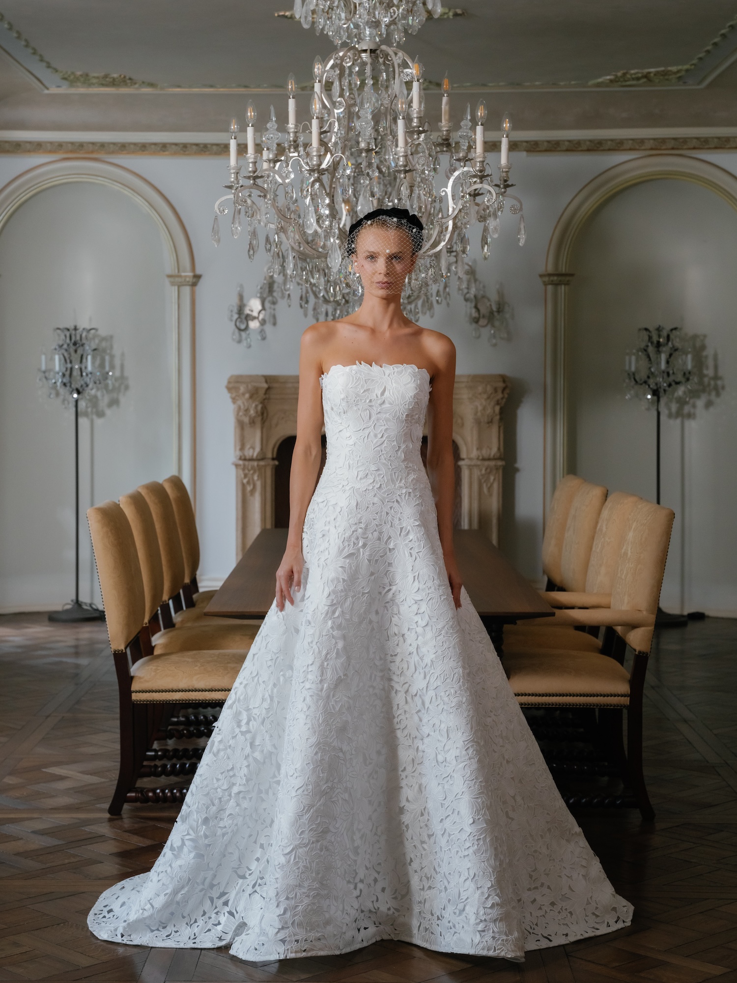 Bride in a luxury dining room in her laser cut lace strapless wedding dress with straight across scallop trim neckline lined bodice with modified aline lined soft coned skirt.