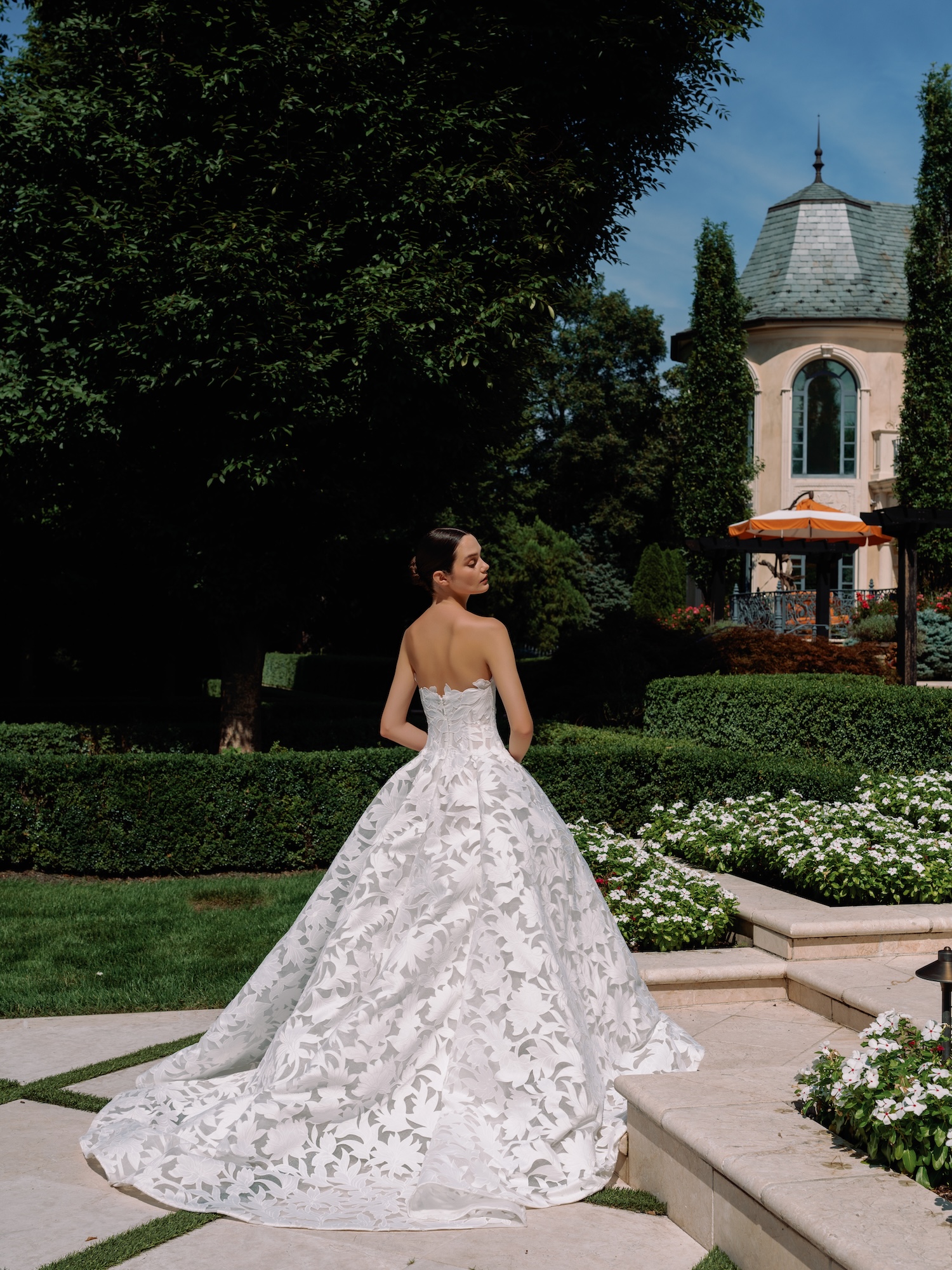 Bride wearing a laser cut organza strapless wedding dress with dropped waist and dramatic semi sheer coned ballgown skirt