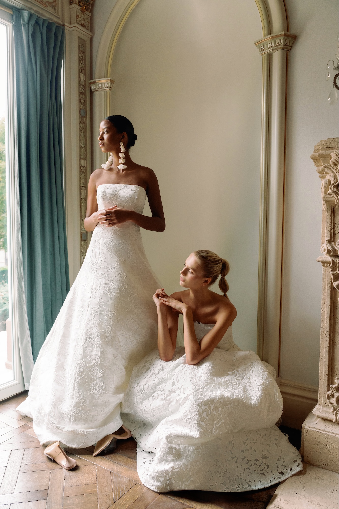 Two brides wearing timeless wedding dresses with lace and floral motif in a luxury villa