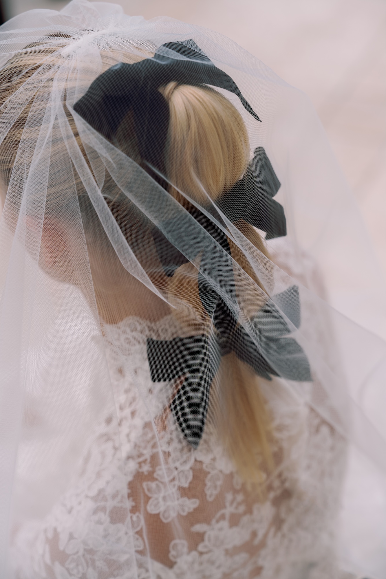 Closeup of bridal ponytail hairstyle with three black bows and a vail covering