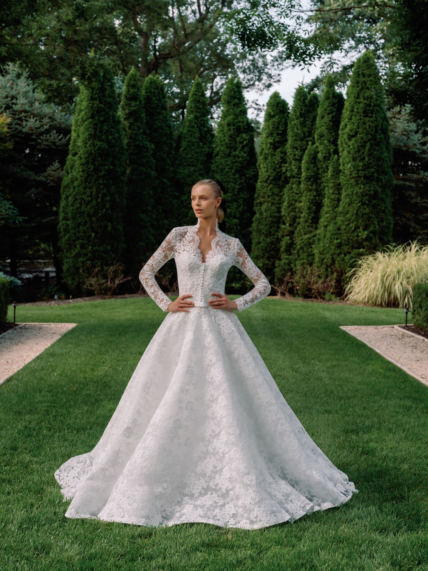Bride with Alencon Lace strapless sweetheart neckline, dropped straight across waist with full ballgown skirt wedding dress standing in the garden